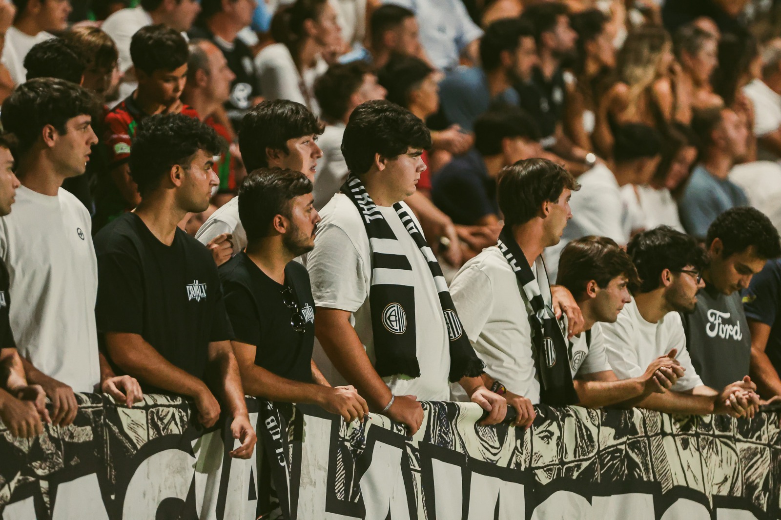 Jóvenes aficionados con bufanda al cuello en la grada